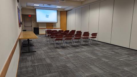 Linda Sickles Meeting Room B with table, projector and screen, and 20 chairs.