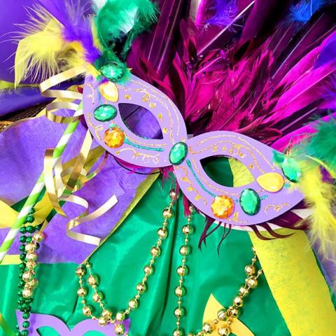 Purple, green, and gold mask with feathers and beads