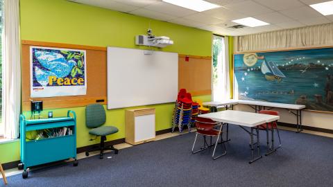 Youth Activity Room - room with table, chairs, mounted whiteboard, and mounted projector