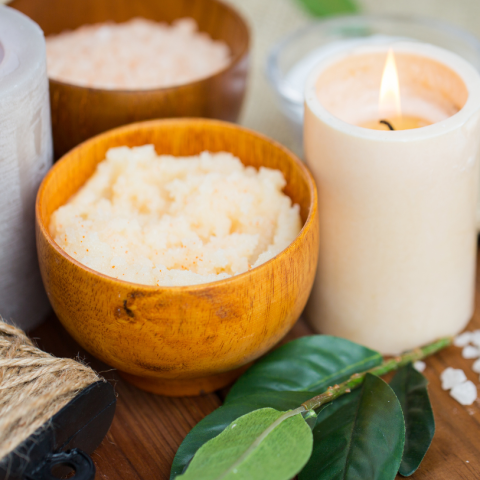 Image of a candle and a bowl with skincare scrub.