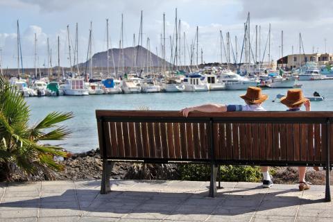 Picture of two people sitting at a bench overlooking a harbor.