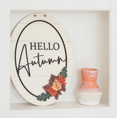 Handmade oval sign with leaves that reads "Hello Autumn". 